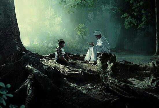 Gambar ayah dan anak belajar mengaji bersama di tengah hutan.